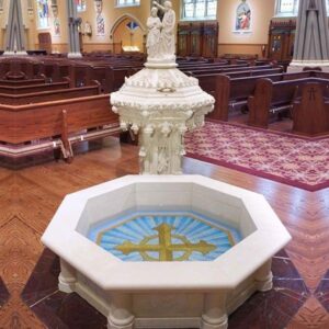 Taufbecken mit Kreuzmosaik im festlich geschmückten Kirchenraum