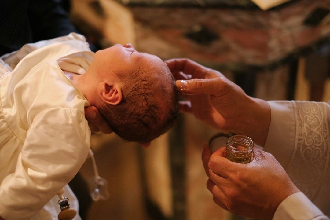 Baby wird bei einer Taufe über einem geöffneten Gefäß gesegnet