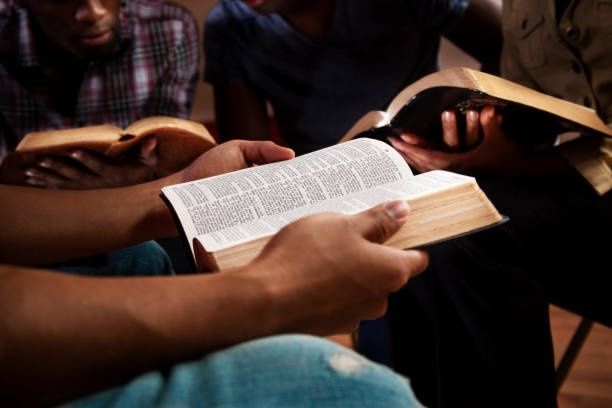 Jugendliche lesen gemeinsam in aufgeschlagenen Bibeln